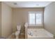 Bathroom with a soaking tub and toilet next to a shuttered window at 7963 Smith Rd, Villa Rica, GA 30180