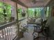 Covered porch with a swing, plants, and an outdoor chair, overlooking the trees at 1597 Leguin Mill Rd, Locust Grove, GA 30248