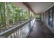 Covered porch with long dark flooring and white railings, overlooking the trees in the background at 1597 Leguin Mill Rd, Locust Grove, GA 30248
