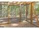 Enclosed porch with wood flooring, open frame, and a view of the surrounding woods at 1597 Leguin Mill Rd, Locust Grove, GA 30248