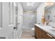 Bright bathroom featuring white tile shower, double sinks, wood cabinets, modern gold fixtures, and wood-look tile at 317 Calgary Dr, Peachtree City, GA 30269