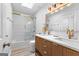 Bright bathroom featuring white tile shower, double sinks, wood cabinets, modern gold fixtures, and wood-look tile at 317 Calgary Dr, Peachtree City, GA 30269