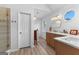 Bright bathroom featuring double sinks, wood cabinets, and a glass shower with modern gold fixtures and wood-look tile at 317 Calgary Dr, Peachtree City, GA 30269