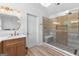 Well-lit bathroom featuring a glass shower, double sink, modern lighting, and wood-look flooring at 317 Calgary Dr, Peachtree City, GA 30269