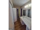 A bathroom featuring a long white vanity with sink, closet doors, and a large mirror at 5128 Running Fox Trl, Norcross, GA 30071