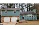 Split level home with a stone base, garage, and front door surrounded by green grass and trees at 5128 Running Fox Trl, Norcross, GA 30071