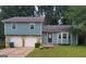 A lovely home features a two-car garage with stone trim and a grassy front lawn at 5128 Running Fox Trl, Norcross, GA 30071