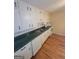 A well-lit kitchen with white cabinets, stainless steel appliances, hardwood floors, and a green countertop at 5128 Running Fox Trl, Norcross, GA 30071