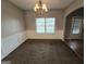 A dining room illuminated by a chandelier, wainscoting, neutral walls, a large window and an arched doorway at 6206 Flat Trace, South Fulton, GA 30291