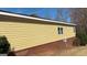 View of the side of the house with bright yellow siding over a brick base and a neatly trimmed lawn at 8828 Patricia Rose, Douglasville, GA 30134