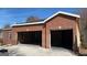 View of a two-car brick garage with an open interior and black ceiling against a blue sky backdrop at 8828 Patricia Rose, Douglasville, GA 30134
