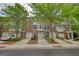 View of brick townhomes with attached garages, complemented by neat landscaping and tree-lined driveways at 2160 Dillard Xing, Tucker, GA 30084