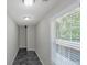 Hallway with view of large window, neutral color paint, and dark tile floors at 90 Heatherstone Way, Covington, GA 30016