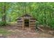Exterior view of a wooden outbuilding with an open front in a wooded backyard at 90 Heatherstone Way, Covington, GA 30016