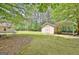 Scenic backyard featuring a shed with car portico, all surrounded by lush greenery and mature trees at 15 Riverside Pkwy, Sharpsburg, GA 30277