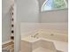 Large bathtub with tile surround, arched window, and privacy curtain at 15 Riverside Pkwy, Sharpsburg, GA 30277