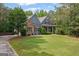 Beautiful blue home featuring stone accents, mature trees, green lawn and welcoming front porch with classic columns at 68 Timber Creek Estates Dr, Sharpsburg, GA 30277