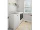Functional laundry room with washer, dryer, shelving, tile floor, and a window for natural light at 68 Timber Creek Estates Dr, Sharpsburg, GA 30277