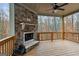 Covered back deck with a cozy stone fireplace and scenic natural views at 5760 Winding Lakes Dr, Cumming, GA 30028