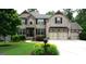 Charming brick home featuring a three-car garage and a beautifully landscaped front yard at 5760 Winding Lakes Dr, Cumming, GA 30028