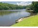 Lakeside property with a wooden dock and steps leading to the water, surrounded by greenery at 3863 Dundee Ne Dr, Roswell, GA 30075