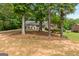 View of a quaint home through several trees and a yard covered in pine straw at 372 River Point Dr, Mcdonough, GA 30252