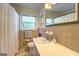 Well-lit bathroom with tan tiling, a shower-tub combo, and single sink vanity at 5327 David Se Cir, Covington, GA 30014