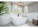 Bathroom featuring a standalone tub, herringbone floors, and natural light from large windows with wooden chandelier above at 1295 Heritage Dr, Villa Rica, GA 30180