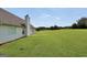 Expansive, green backyard with view of home's exterior featuring chimney and manicured lawn at 502 Gallantry Trl, Mcdonough, GA 30252