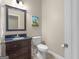 Bathroom featuring a dark vanity, tile flooring, toilet, and decorative art at 570 Mcgarity Dr, Mcdonough, GA 30252