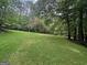 Large backyard featuring mature trees, lush green grass and lots of space for outdoor activities at 715 Frog Rd, Locust Grove, GA 30248