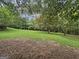 View of the backyard showing a large, flat, grassy area with trees on a sunny day at 715 Frog Rd, Locust Grove, GA 30248