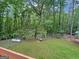 Large grassy backyard featuring mature trees, a dog house, and full perimeter fencing at 715 Frog Rd, Locust Grove, GA 30248