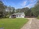 View of home with a long driveway, lush green lawn, and tall trees in the background at 401 Grove Pointe Ct, Locust Grove, GA 30248