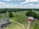 Expansive aerial view of a property with lush green fields, a barn, and mature trees on a sunny day at 382 Knox Chapel Rd, Social Circle, GA 30025