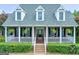 Charming brick home with dormer windows and a welcoming front porch with hanging ferns and white railings at 382 Knox Chapel Rd, Social Circle, GA 30025