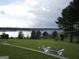 Scenic lake view from a property with Adirondack chairs on a lush, green lawn at 1141 Pebble Creek Ln, Locust Grove, GA 30248