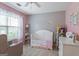 A cute room with pink walls, a crib, and a neutral colored rocking chair at 243 Kensington Trce, Stockbridge, GA 30281