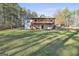 Back exterior of home with large lawn, lower patio and deck, and access to wooded area at 1234 Coweta Heard Rd, Hogansville, GA 30230