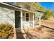 Covered front porch featuring white support beams and a dark screen door, flanked by mature landscaping at 8479 Alden Dr, Riverdale, GA 30274