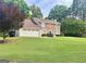 Charming two-story brick home with a manicured lawn and an attached two-car garage at 130 Floss Flower Ct, Roswell, GA 30076