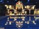 A backyard pool reflecting the lights of a home at night, framed by stone pillars at 130 Floss Flower Ct, Roswell, GA 30076