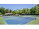 Well-maintained tennis courts with blue and green surfaces, surrounded by lush green trees at 130 Floss Flower Ct, Roswell, GA 30076