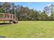 View of the backyard highlighting a large grassy area and the wooden deck with stairs from a different angle at 2955 Peeksville Rd, Locust Grove, GA 30248