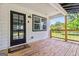 A covered porch with a wood floor has a 