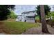 Wide backyard with new white siding on the home, green grass, and bordered by mature trees at 303 Sedgewick Trl, Lawrenceville, GA 30044