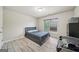 Neutral bedroom featuring wood-look flooring, a window with blinds, and a bed with a gray headboard at 1979 Alcovy Shoals Blf, Lawrenceville, GA 30045