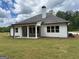 Back view of home with a covered patio overlooking a green lawn and surrounding trees at 555 Discovery Lake Dr, Fayetteville, GA 30215