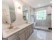 Bathroom featuring double sinks, quartz countertops, oval mirrors, and tiled shower at 5582 Rockingwood Ct, Atlanta, GA 30349