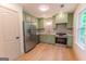 Well-lit kitchen features stainless steel appliances, sage green cabinets and hardwood flooring at 5582 Rockingwood Ct, Atlanta, GA 30349